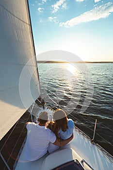 Family Of Three Sitting On Yacht Boat Deck Outdoors, Vertical