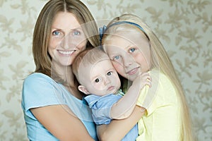 Family of three smiling and hugging people indoor portrait