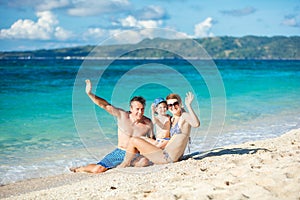 Family of three waving hands while having fun on the beach