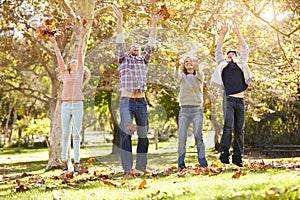 Family Throwing Autumn Leaves In The Air