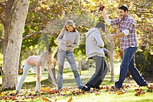 Family Throwing Autumn Leaves In The Air