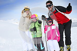 Family with thumbs up for snow holidays in a ski resort