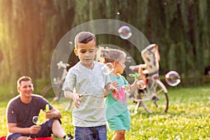 Family time- Cheerful children chase bubbles in nature