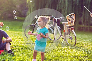 Family time- Cheerful girl chase bubbles in nature