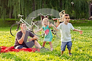 Family time- father with children blow soap bubbles outdoor