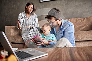 Family time- father reading book for little baby son at home