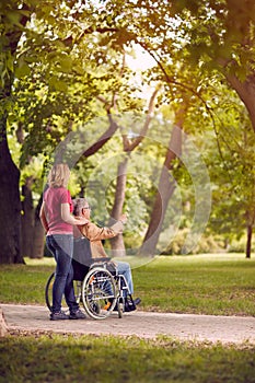 Family time- senior man in wheelchair and daughter in the park