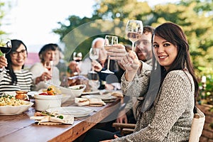 The family together again. a group of cheerful people raising their wine glasses to toast over a diner table while