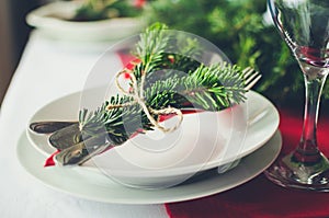 Family together Christmas celebration dinner table concept. Festive place setting for holiday dinner with natural decorations from