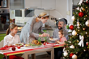 Family together at decorated table having festively dinner photo