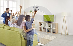 Family together emotionally cheer for national team while watching football match at home.