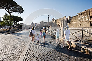 Family tourists walking in street Via dei Fori Imperiali in Rome, Italy