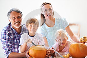 Family traditions. Portrait of a family of four hollowing out pumpkins for halloween.