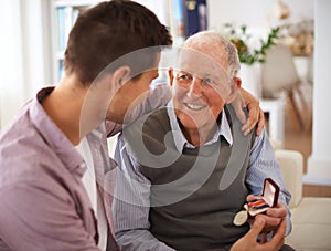 family traditions. a senior father giving his son a medal while theyre sitting indoors.