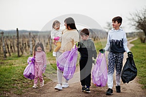 Family with trash bag collecting garbage while cleaning in the vineyards . Environmental conservation and ecology, recycling