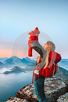 Family travel lifestyle - mother lifting up infant baby outdoor hiking in Norway summer vacations in Lofoten islands