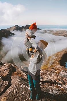 Family travel mother hiking holding up child on mountain summit