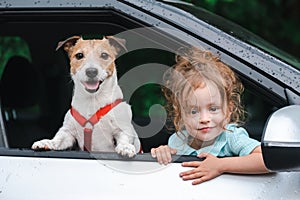 Family traveling by car. Little girl and pet dog looking out of car window waiting for spring rain to stop