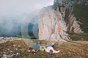 Family traveling relaxing in mountains mother and father with child laying on grass together