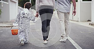 Family, trick or treat in street on Halloween with child and parents holding hands on holiday. Dad, mom and kid with