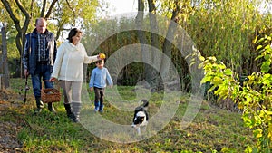 Family trip to nature, elderly people with grandchildren walk at autumn park with dog