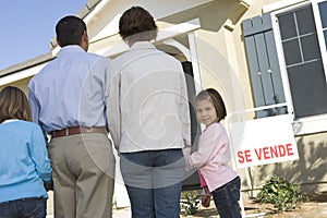 Family with two children (6-8) in front of new house back view