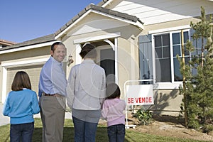 Family with two children (6-8) in front of new house back view