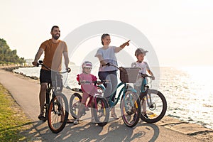 Family with two children on bikes, standing near the sea