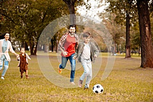 Family with two children running and playing soccer together in an