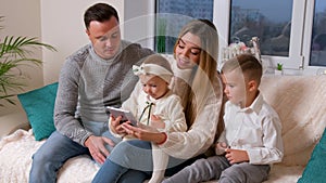 Family with two kids speaking with grandmother on web camera making hi sign.