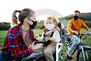 Family with two small children on cycling trip, wearing face masks.