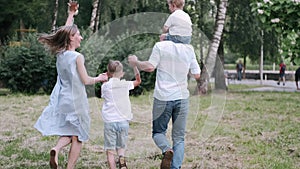 Family with two sons is walking together in the summer park