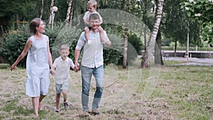 Family with two sons is walking together in the summer park