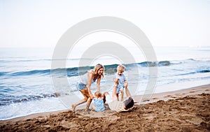 A family with two toddler children lying on sand beach on summer holiday.