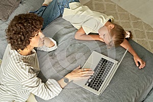 Family of two using laptop in bedroom