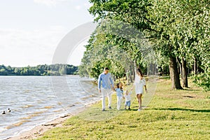 A family with two young children walks along the shore of the lake
