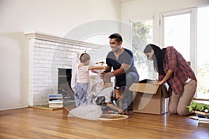 Family Unpacking Boxes In New Home On Moving Day