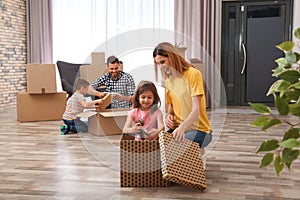 Family unpacking cardboard boxes in their new house