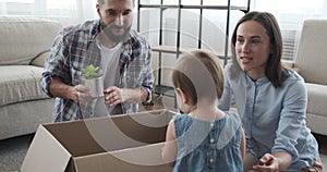 Family unpacking carton box together in new house