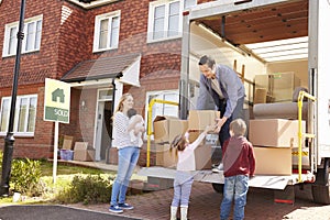 Family Unpacking Moving In Boxes From Removal Truck