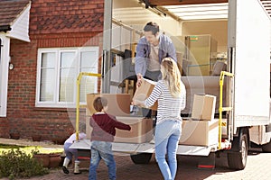 Family Unpacking Moving In Boxes From Removal Truck