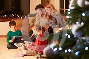 Family Unwrapping Gifts By Christmas Tree