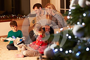 Family Unwrapping Gifts By Christmas Tree