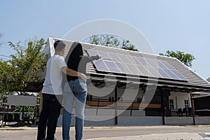 Family uses renewable energy system with solar panel. Rear View Of A Young Couple Standing In Front Of Their New House