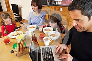 Family Using Gadgets Whilst Eating Breakfast