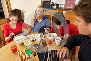 Family Using Gadgets Whilst Eating Breakfast