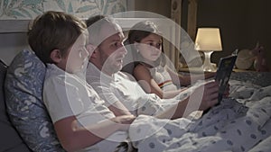 Family using laptop in bed.