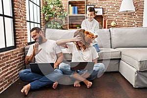 Family using laptop and kid bothering their parents at home