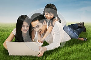 Family using laptop on the meadow