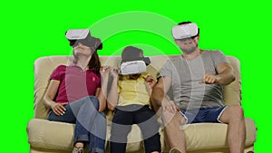 Family using VR glasses sitting on the sofa. Green screen